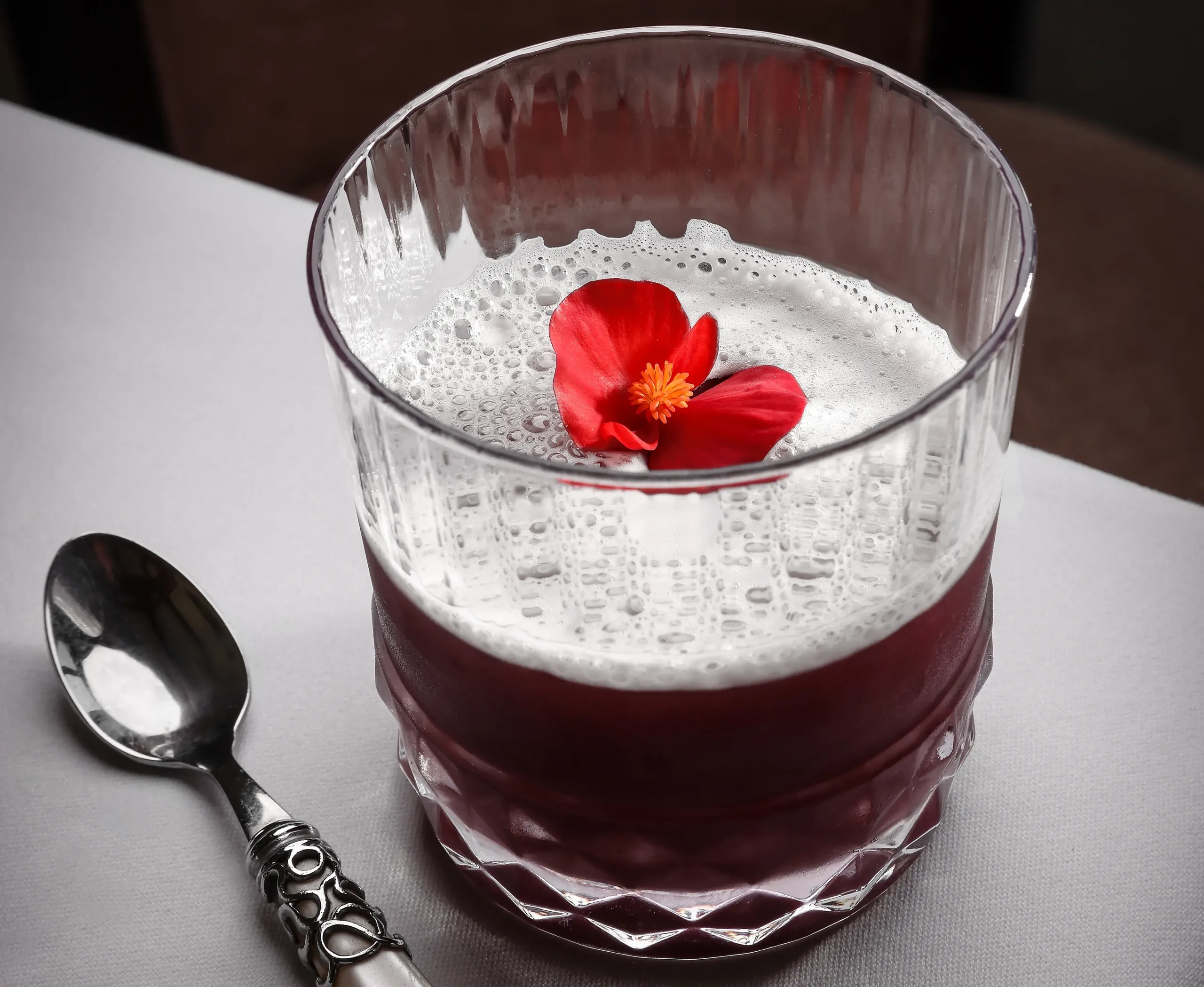 Verre avec mousse et fleur rouge, cuillère à côté.