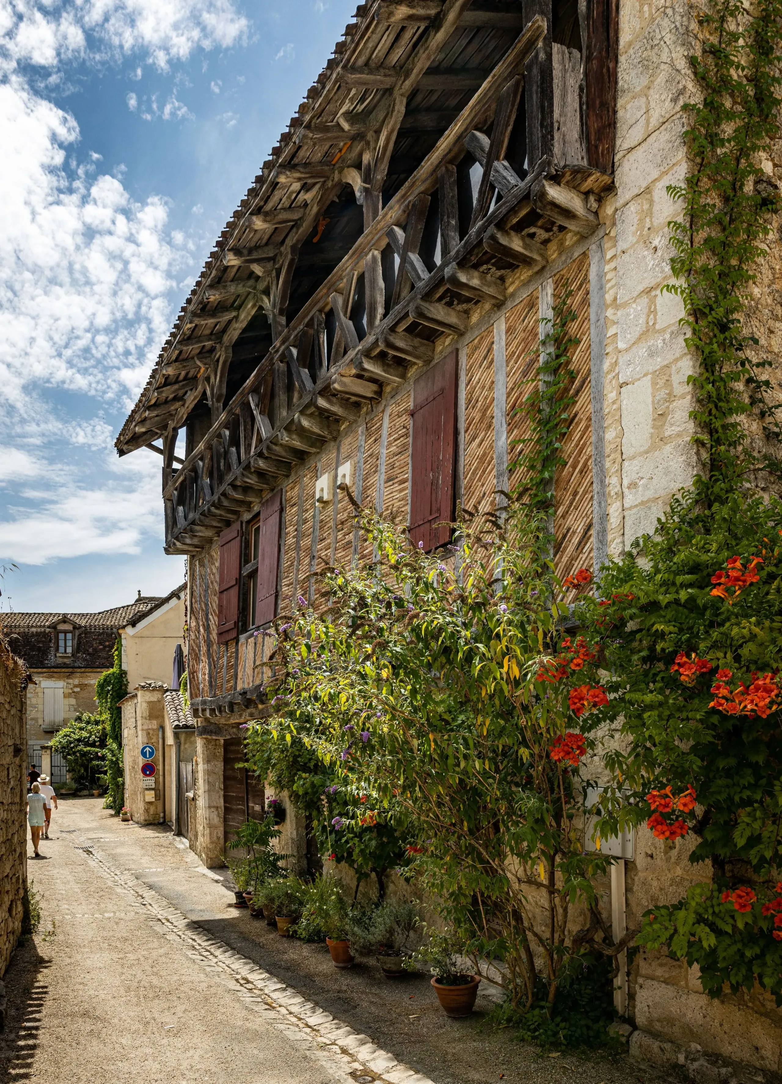 Rue pittoresque avec maison à colombages et fleurs.