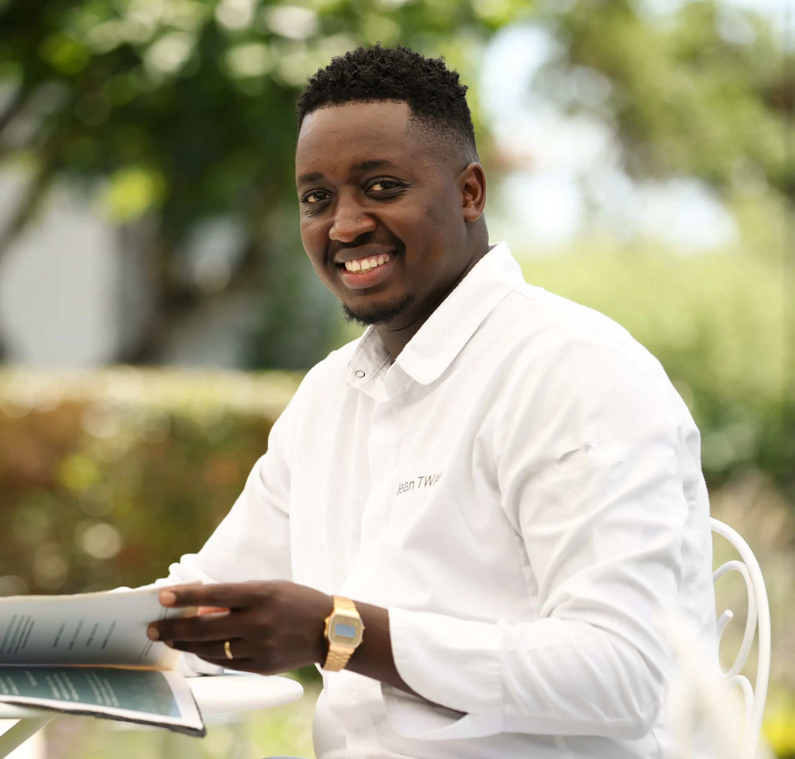 Homme souriant avec magazine en extérieur.