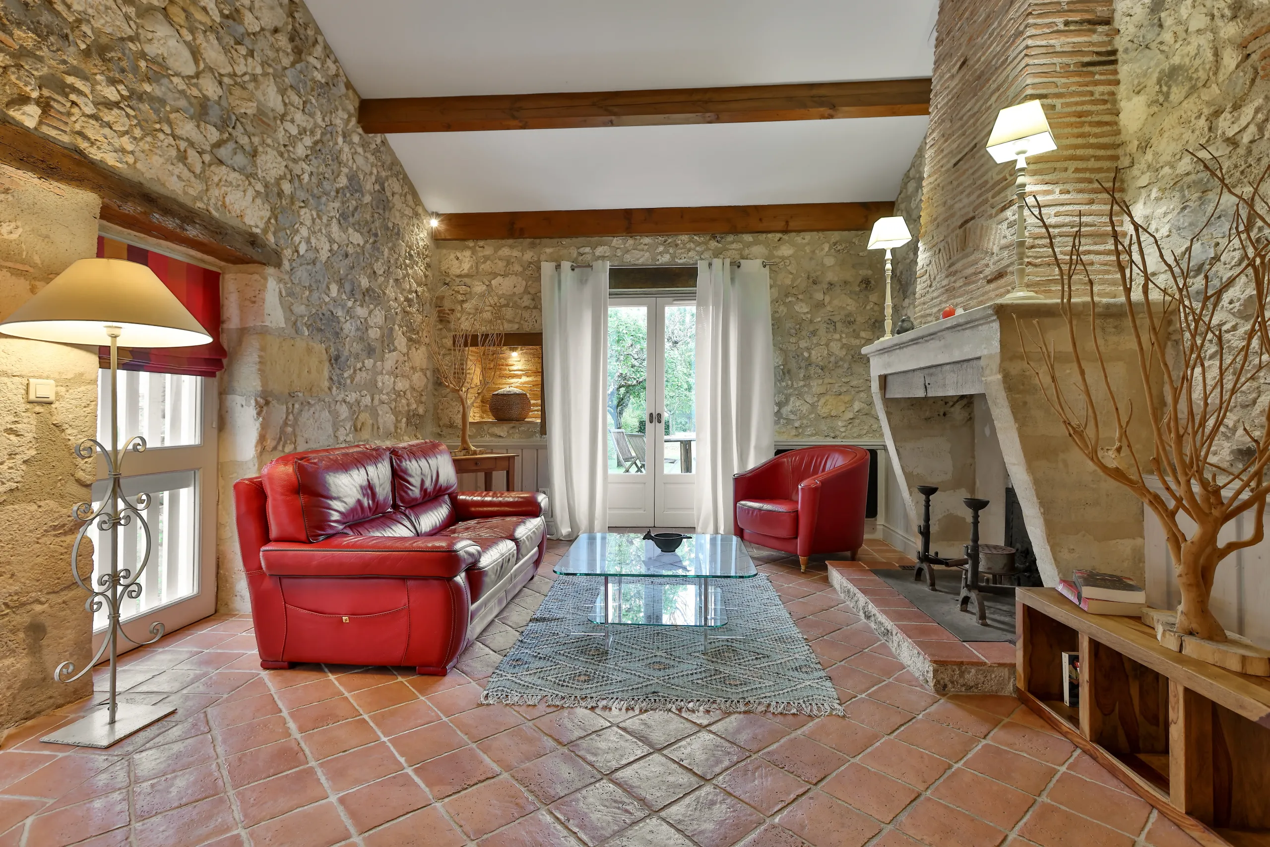 Salon rustique avec canapé rouge et cheminée.