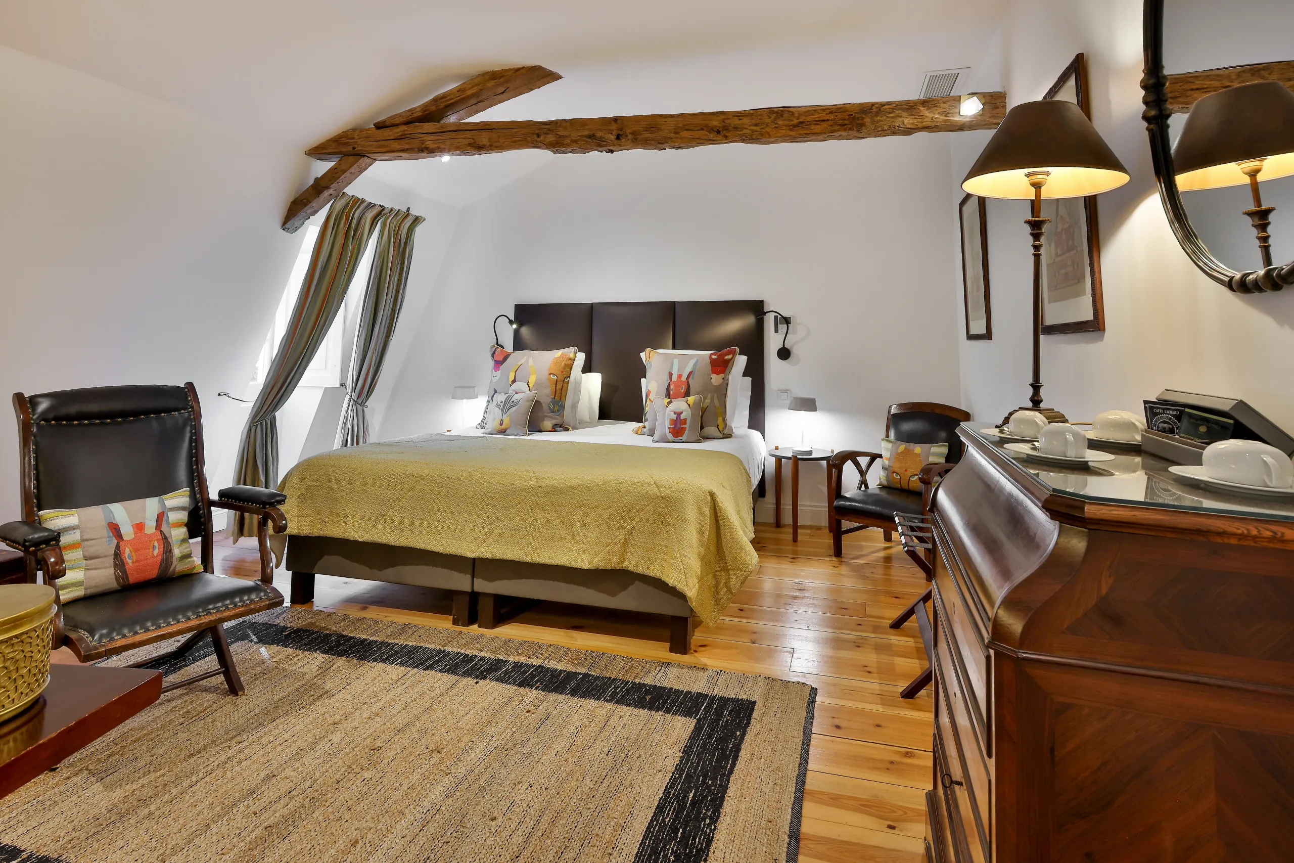 Chambre lumineuse avec lit double et fauteuils en cuir.