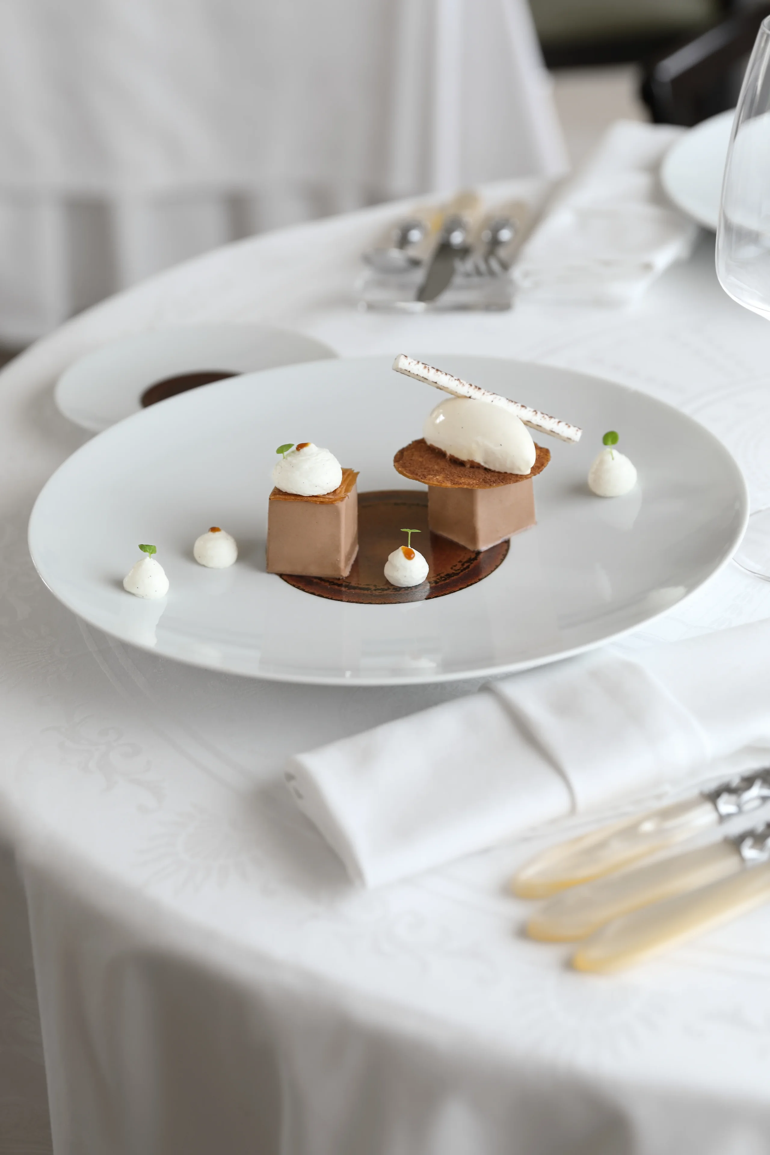 Assiette de dessert gastronomique sur table blanche.
