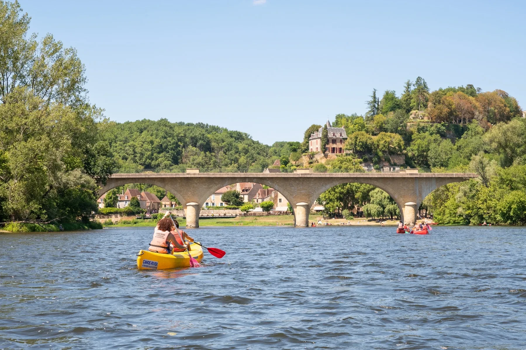 Kayak sur rivière près d'un pont en pierre.