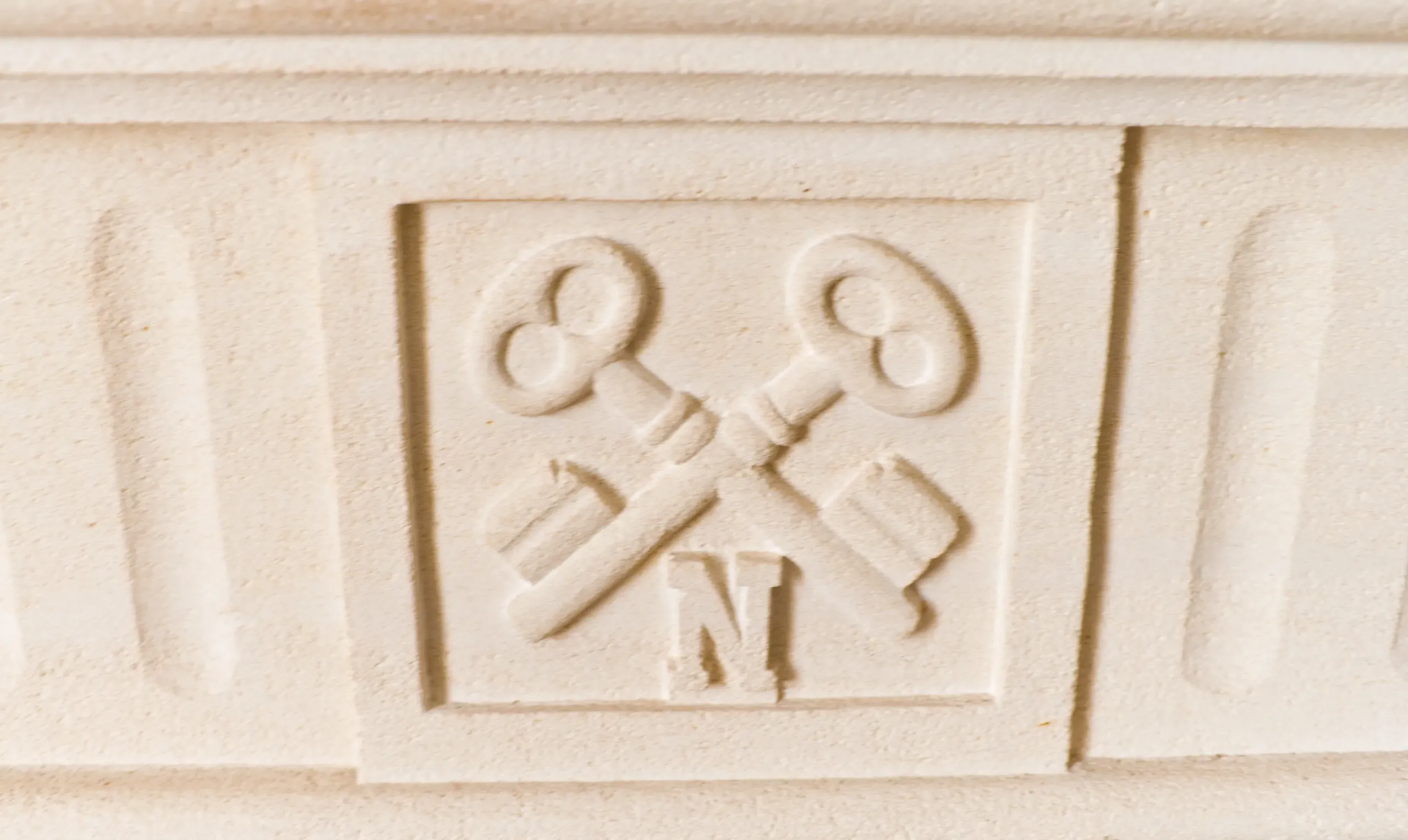Relief de clés croisées sur pierre blanche.