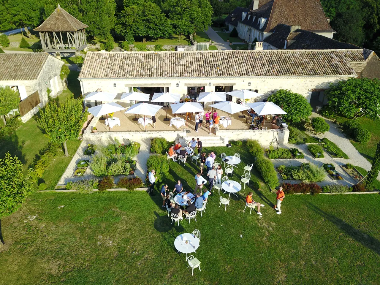 Vue aérienne d'un jardin et terrasse avec invités.
