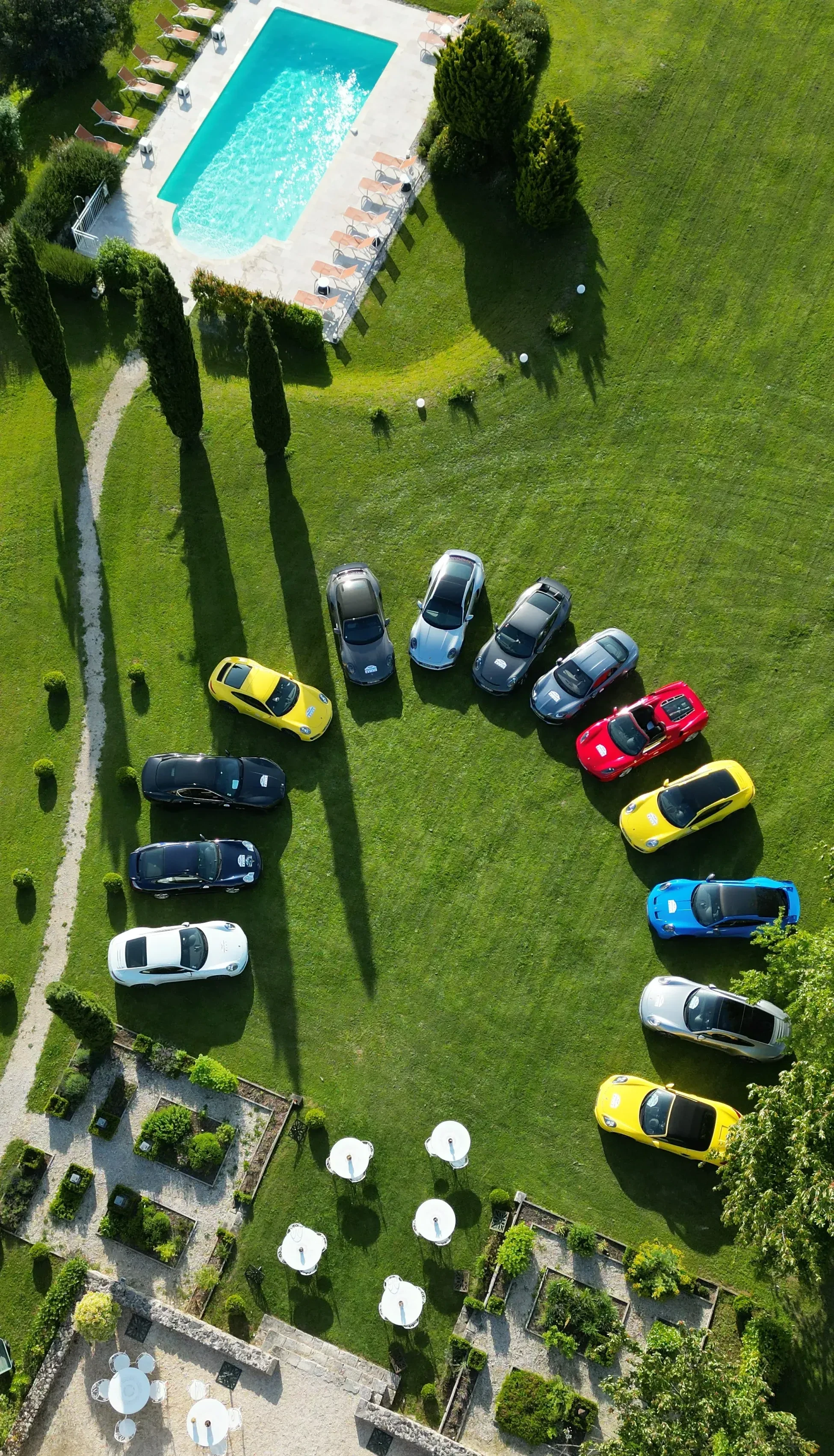Voitures colorées autour d'une piscine, vue aérienne.
