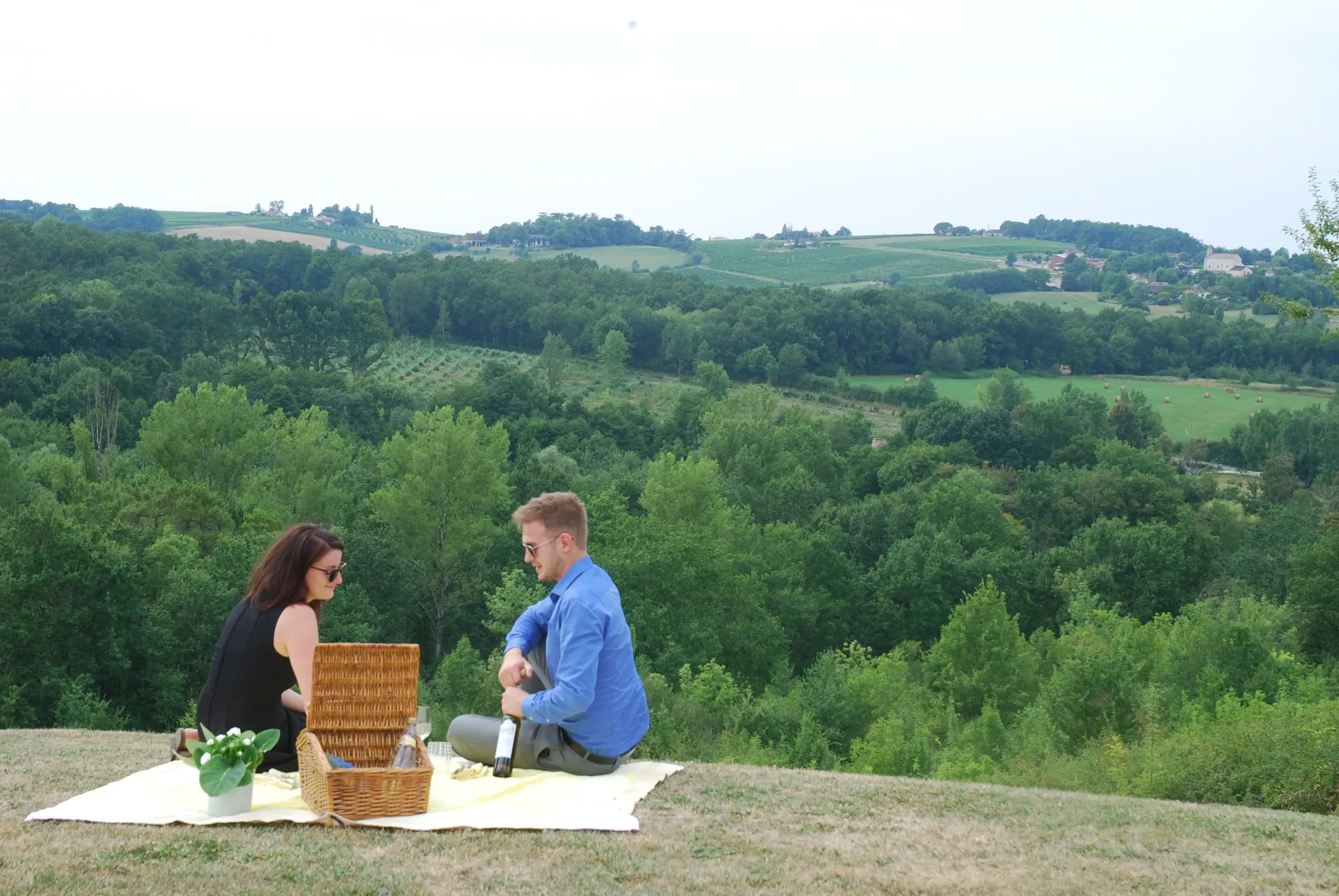 Pique-nique en couple devant paysage verdoyant.