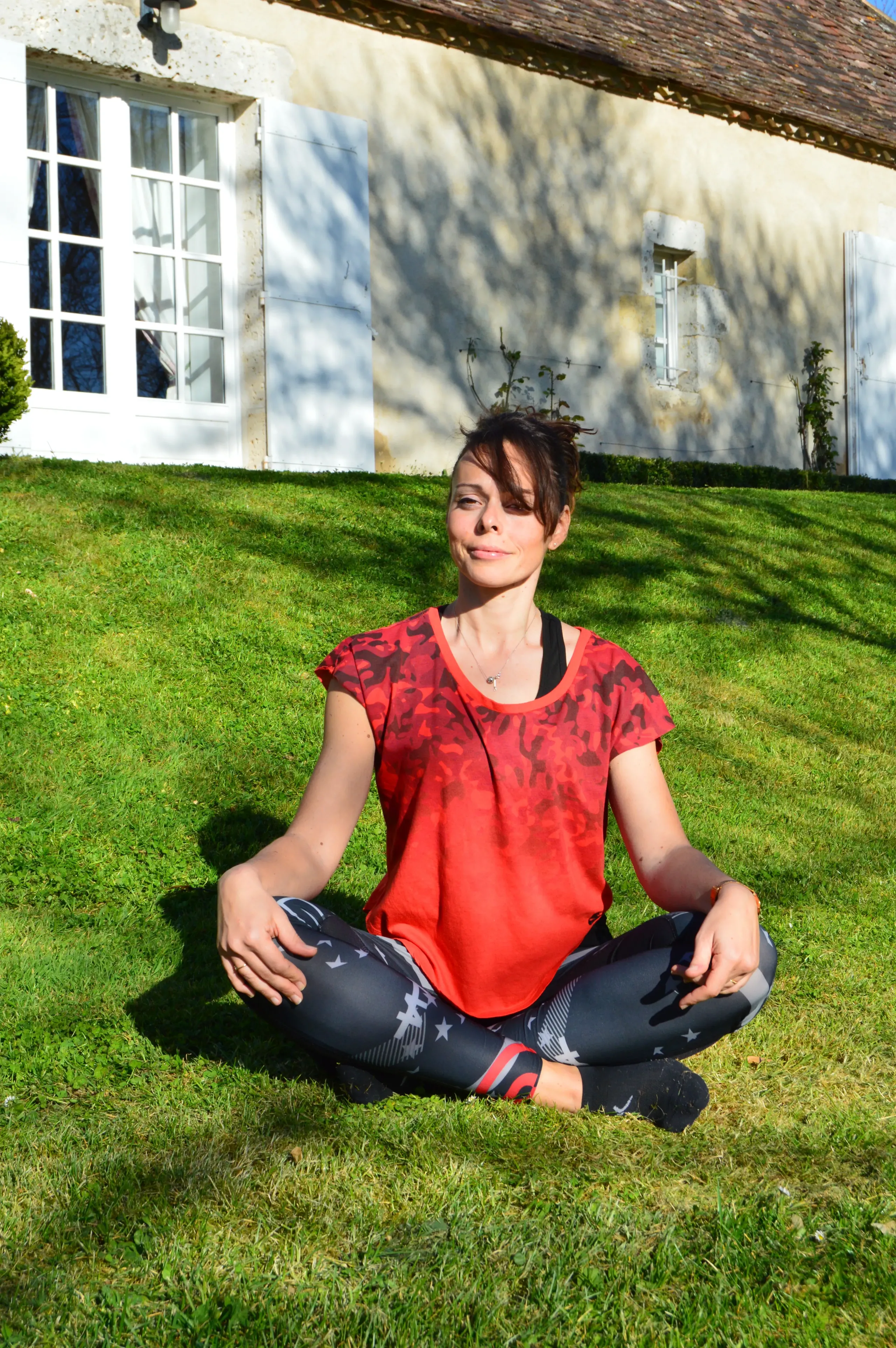 Femme méditant à l'extérieur sur l'herbe verte.