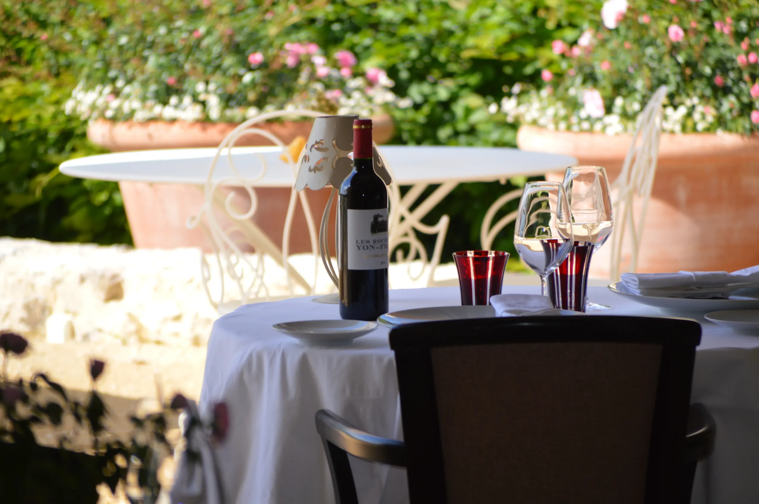 Table avec vin et verres en terrasse verdoyante.