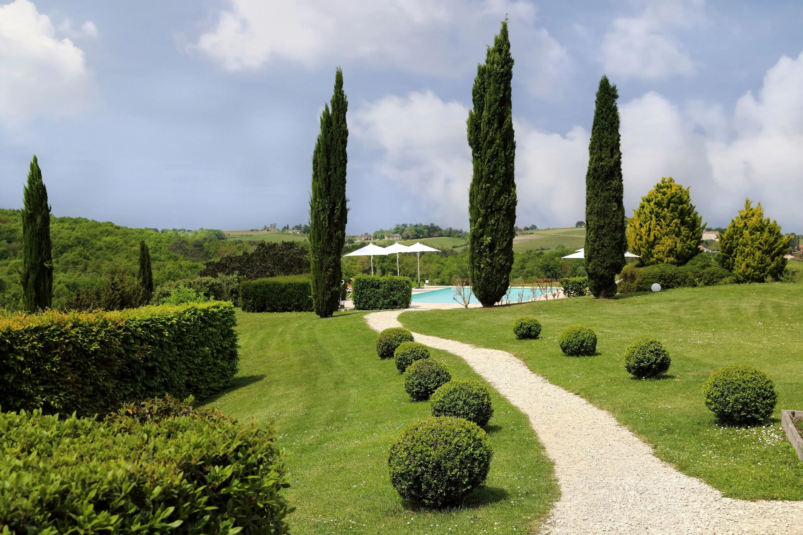 Jardin verdoyant avec chemin et cyprès