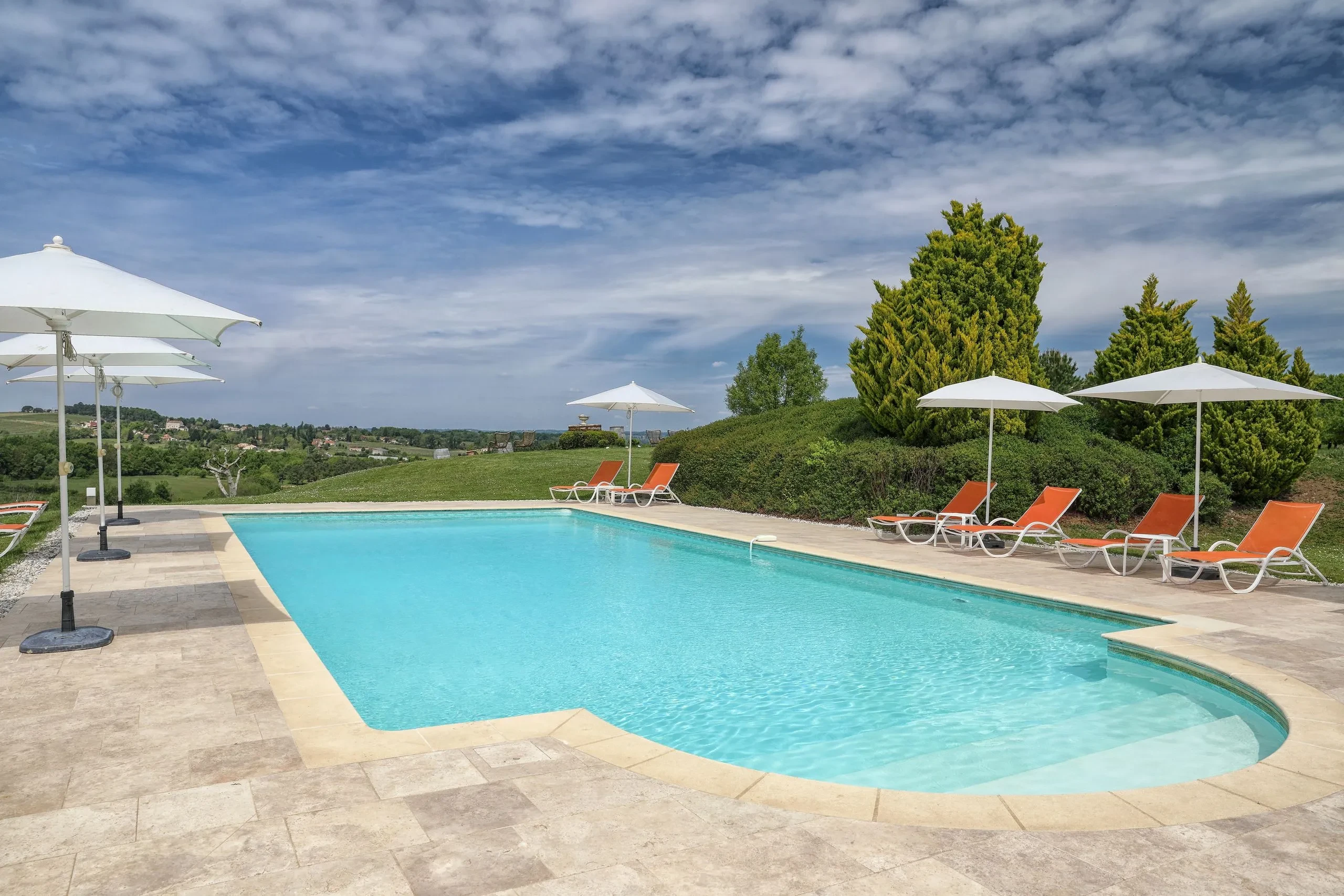 Piscine extérieure avec chaises longues et parasols.
