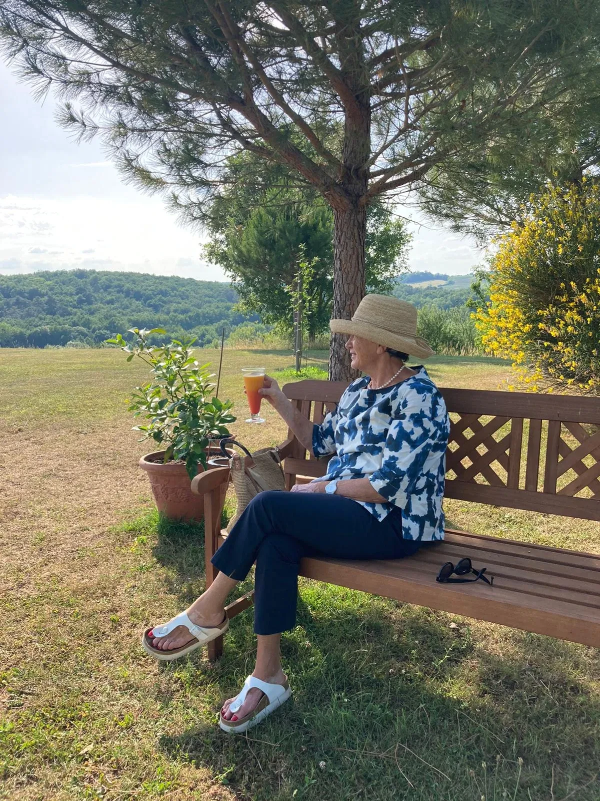 Personne assise sur un banc, boisson à la main.
