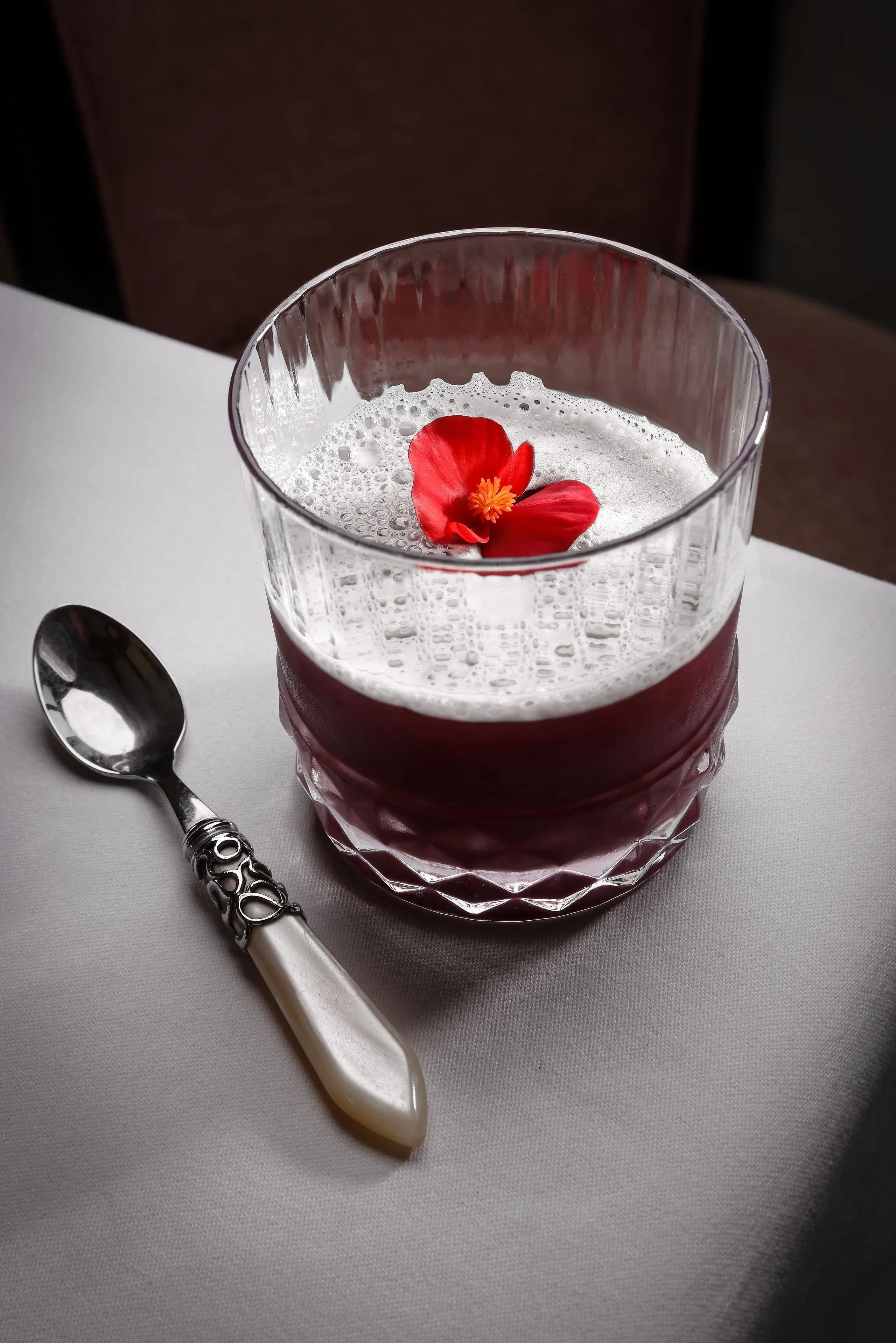 Verre avec mousse et fleur rouge.