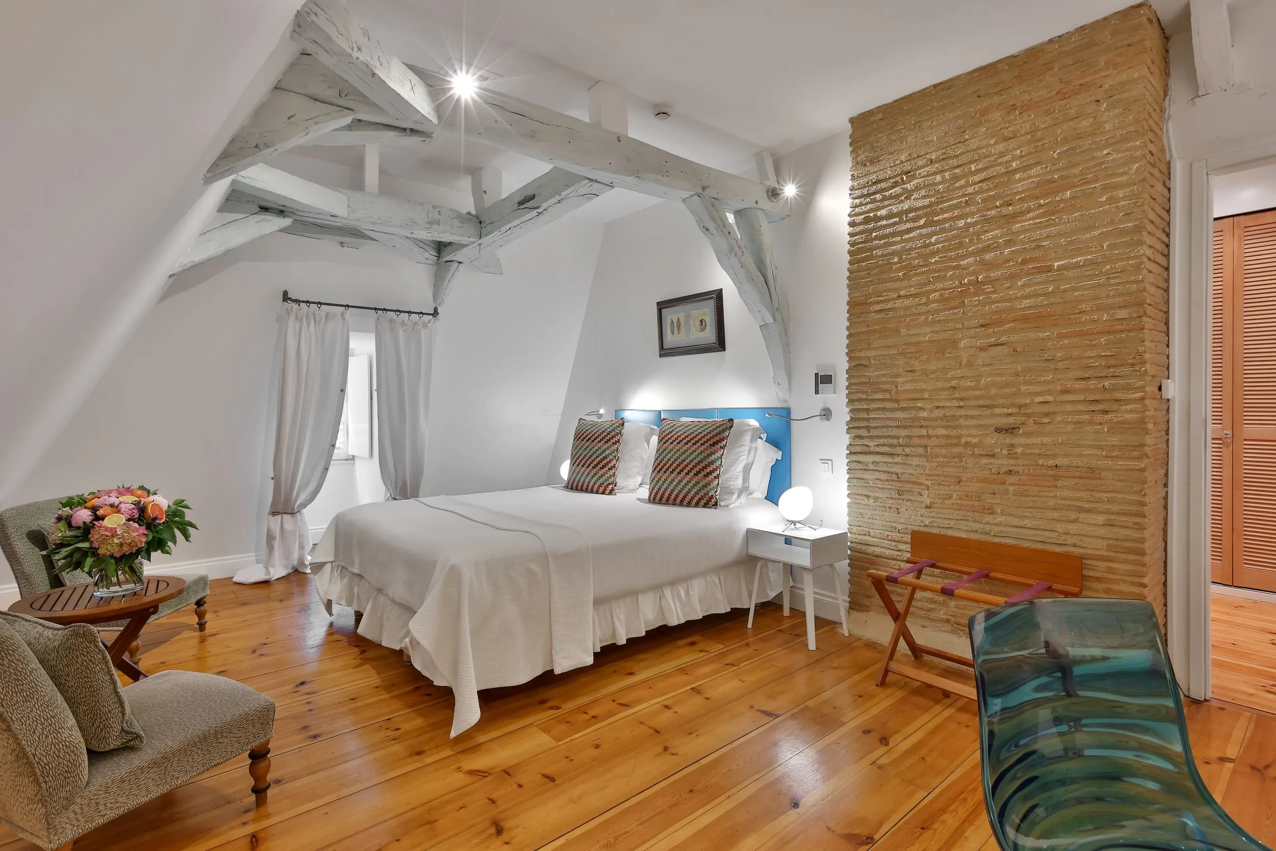 Chambre lumineuse avec lit double et poutres apparentes.