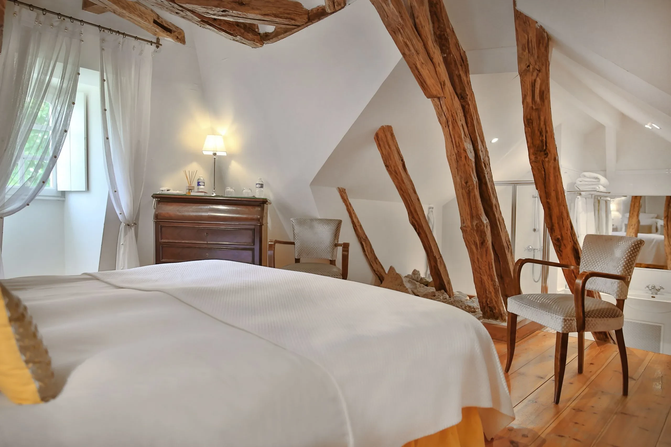 Chambre mansardée avec lits et poutres apparentes.