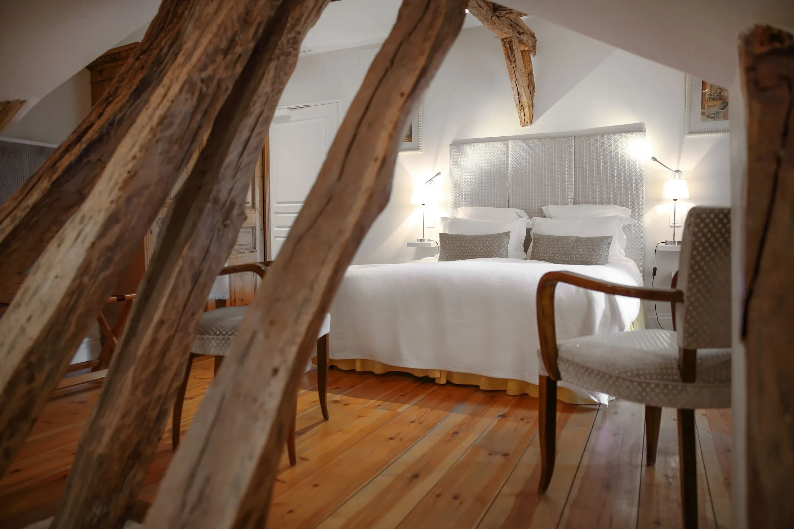 Chambre lumineuse avec poutres apparentes et lit double.
