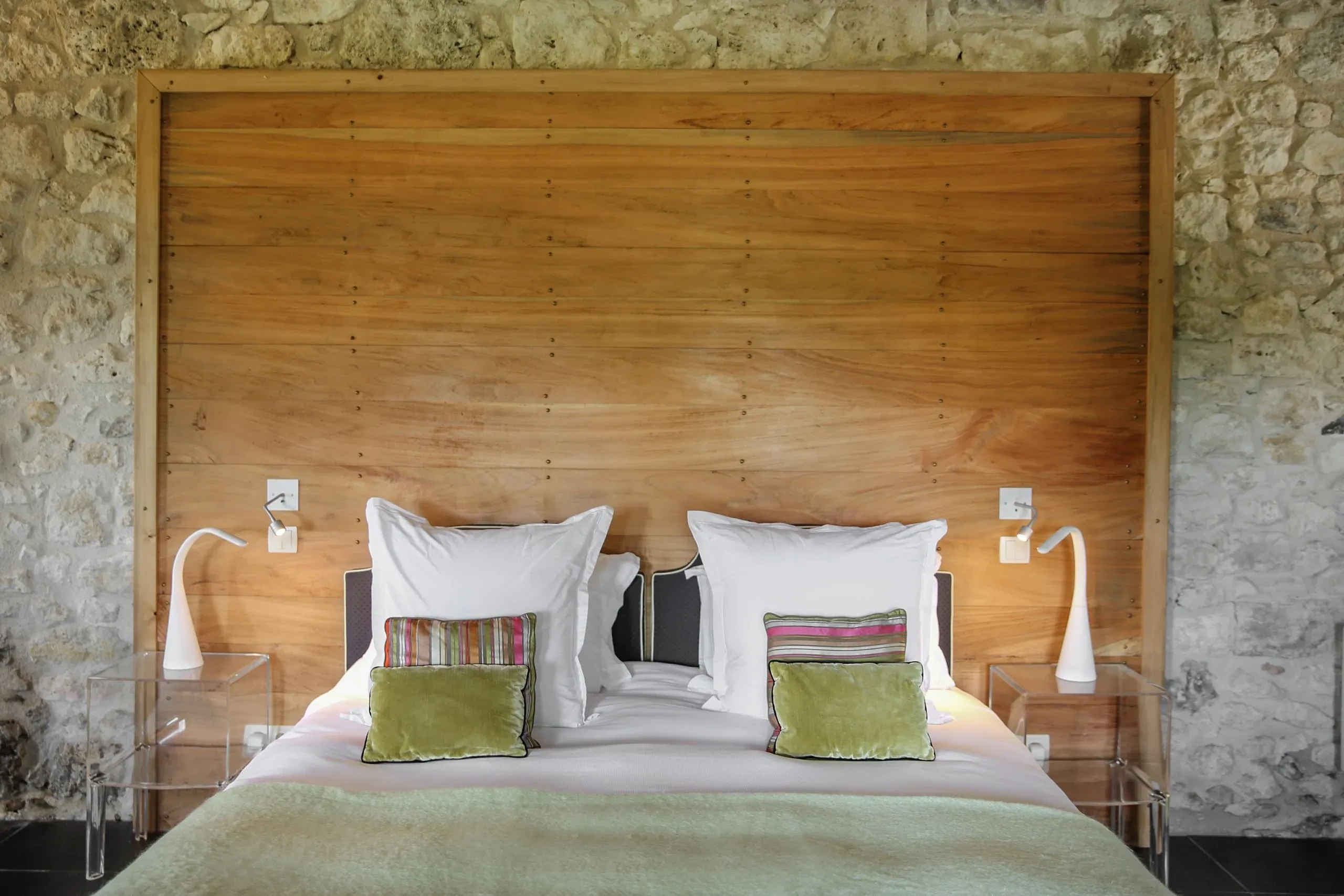 Lit avec coussins colorés et tables de chevet.