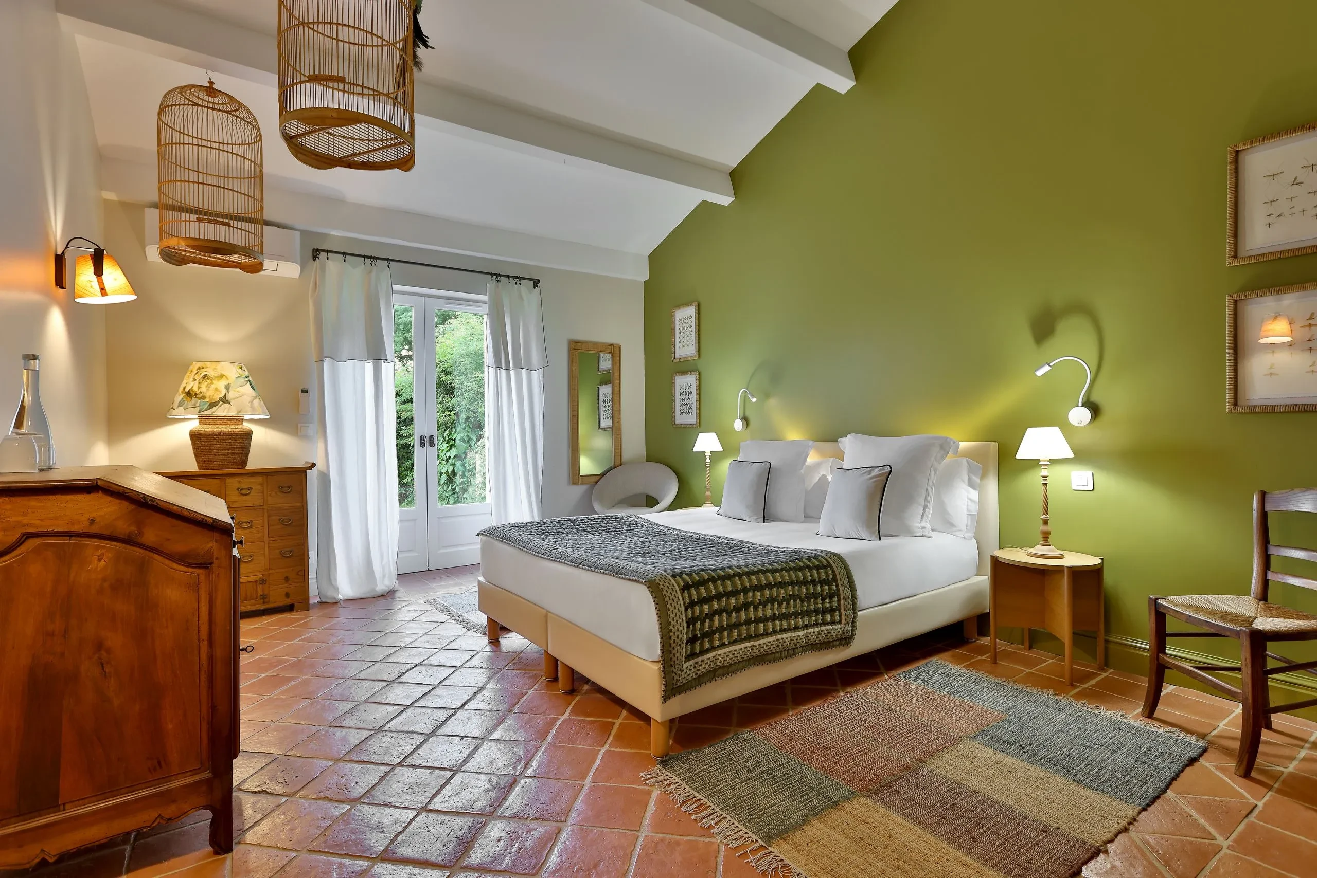 Chambre lumineuse avec murs verts et parquet en terre cuite.