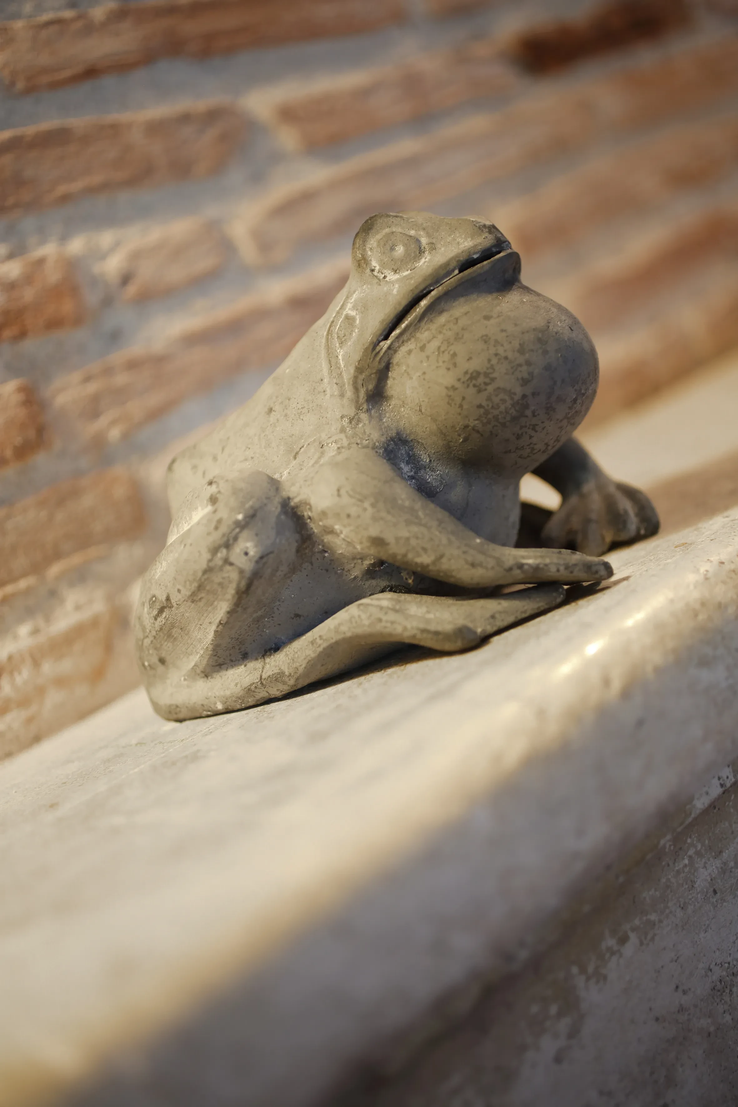 Statue de grenouille en pierre sur un banc.