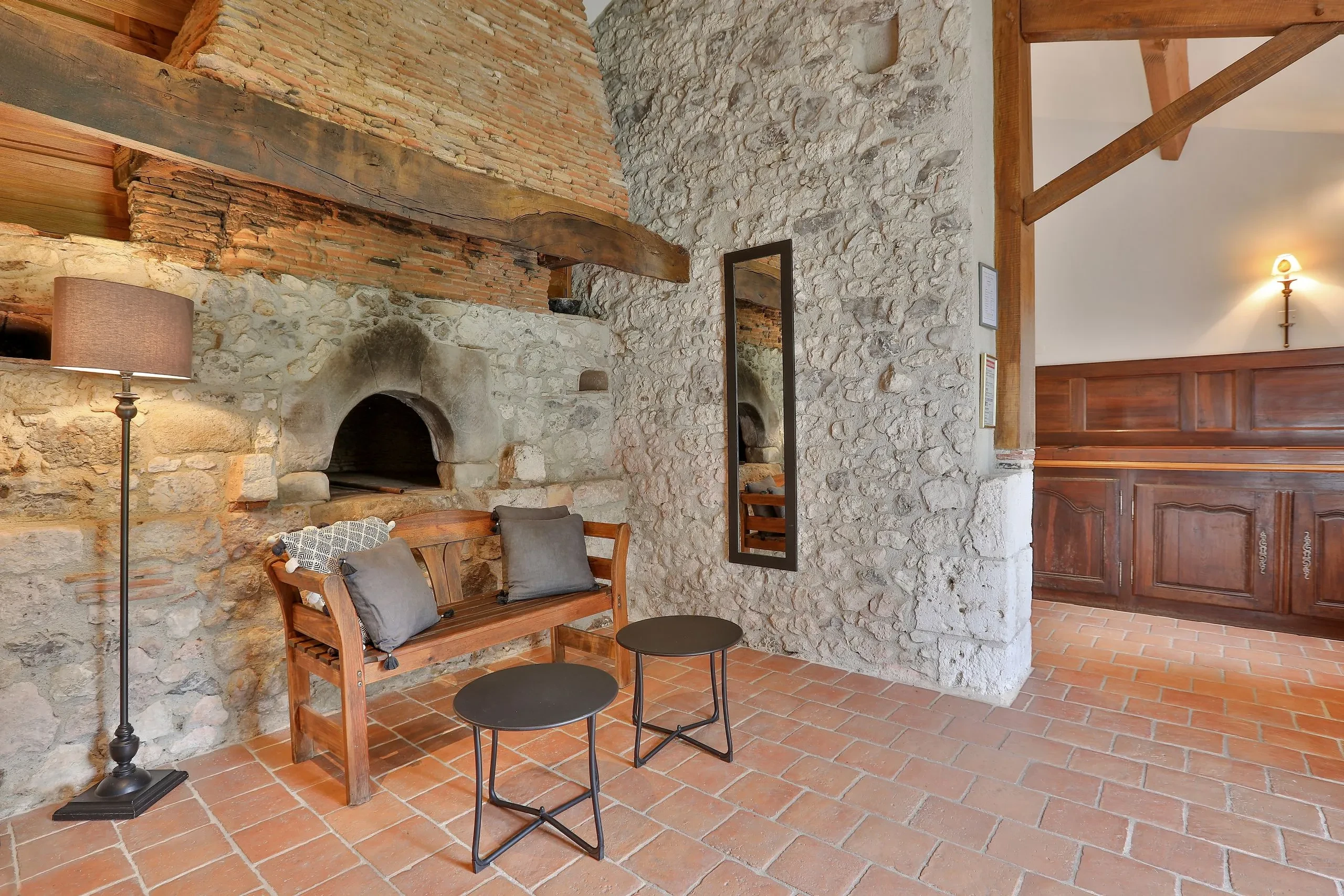 Salon rustique avec murs en pierre et banc en bois.