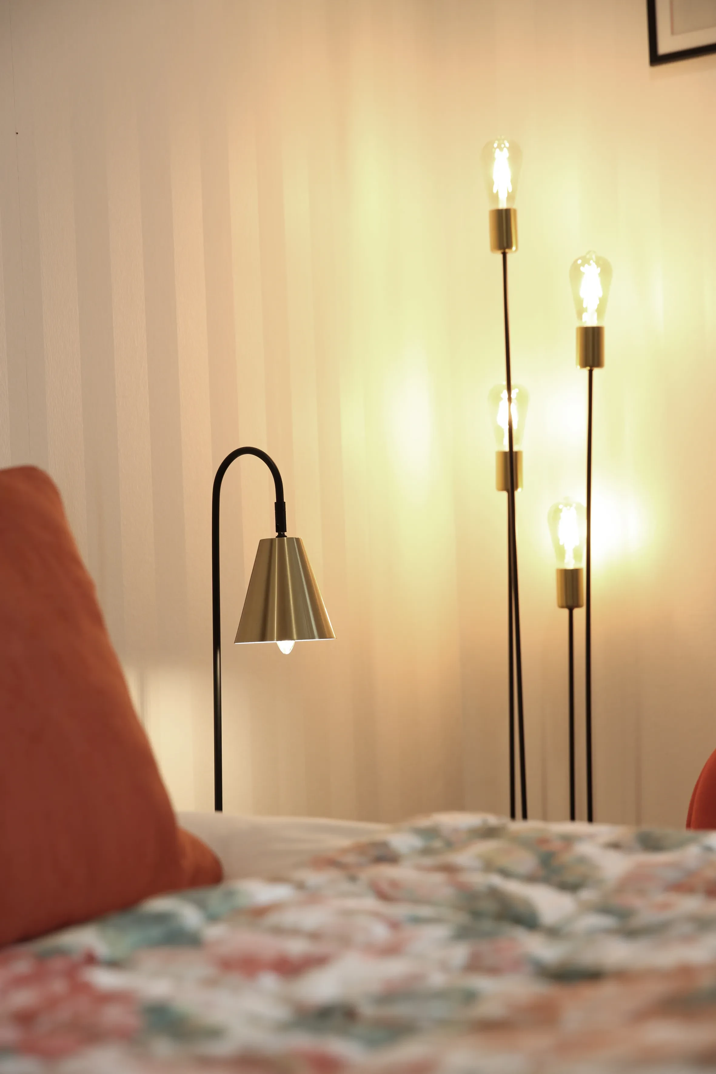 Chambre lumineuse avec lampes et oreiller orange.