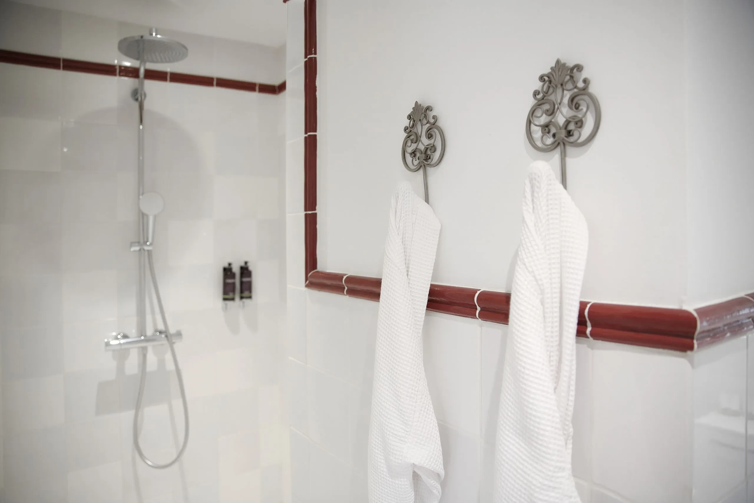 Salle de bain avec douches et peignoirs suspendus.