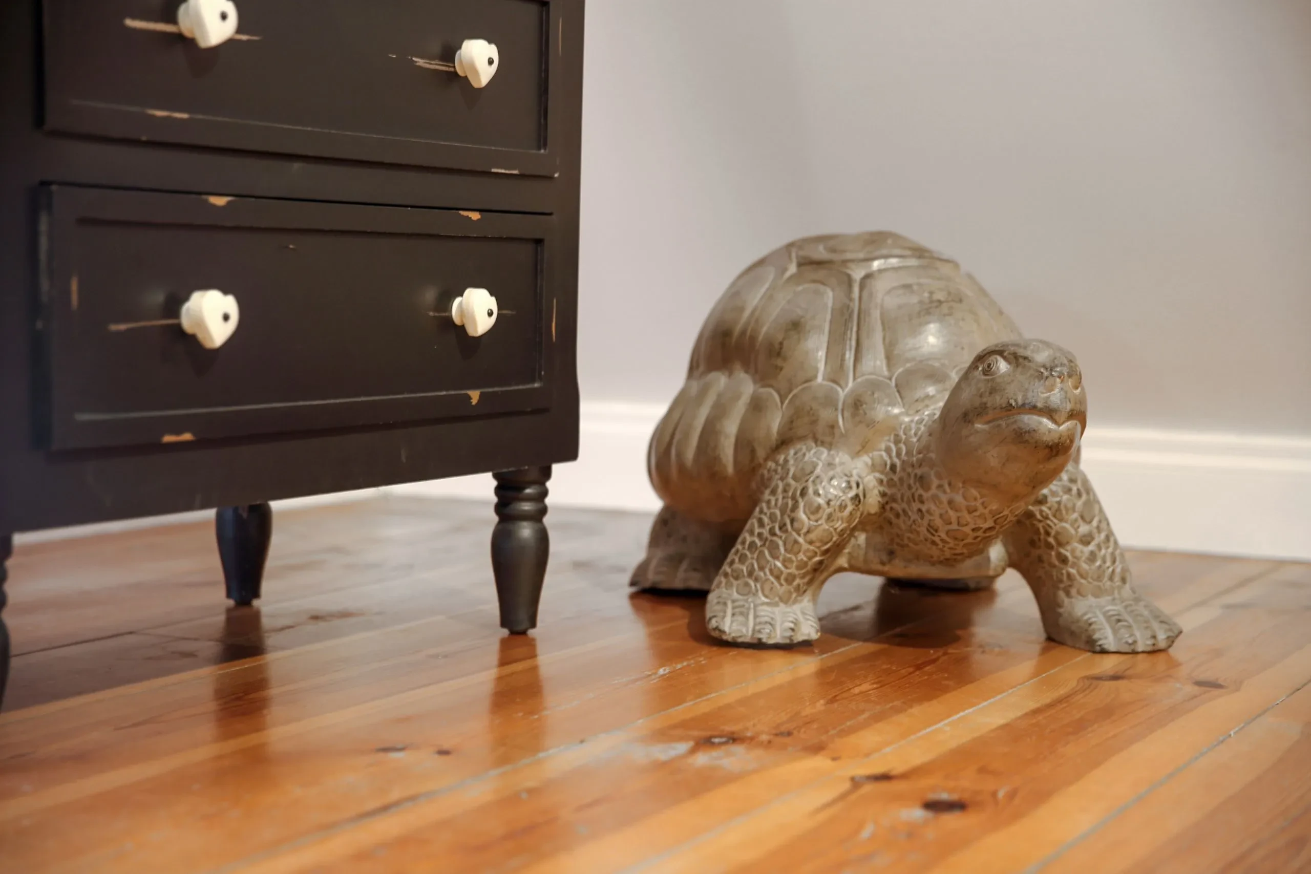 Sculpture tortue à côté d'un meuble noir.