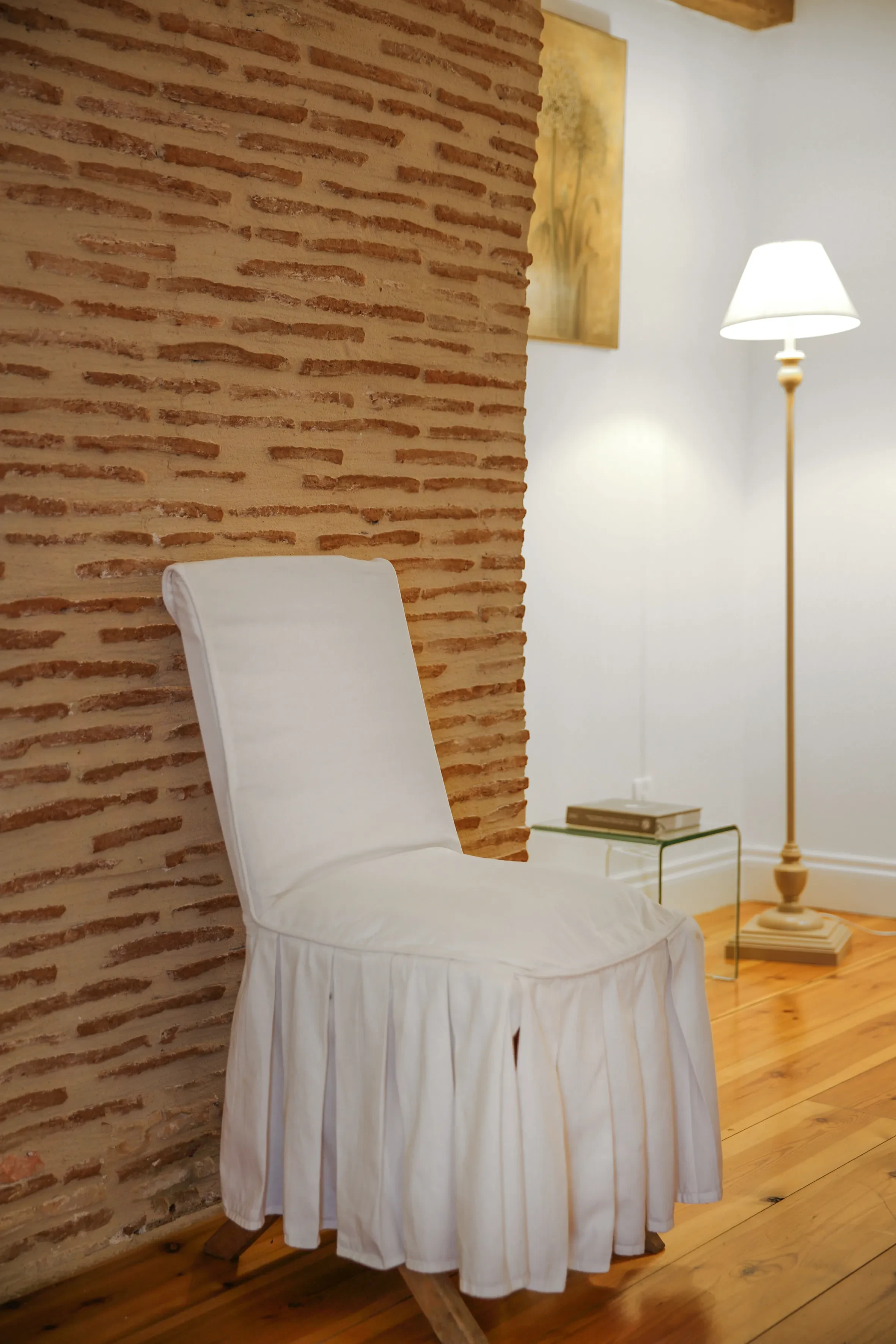 Chaise blanche devant mur en briques.