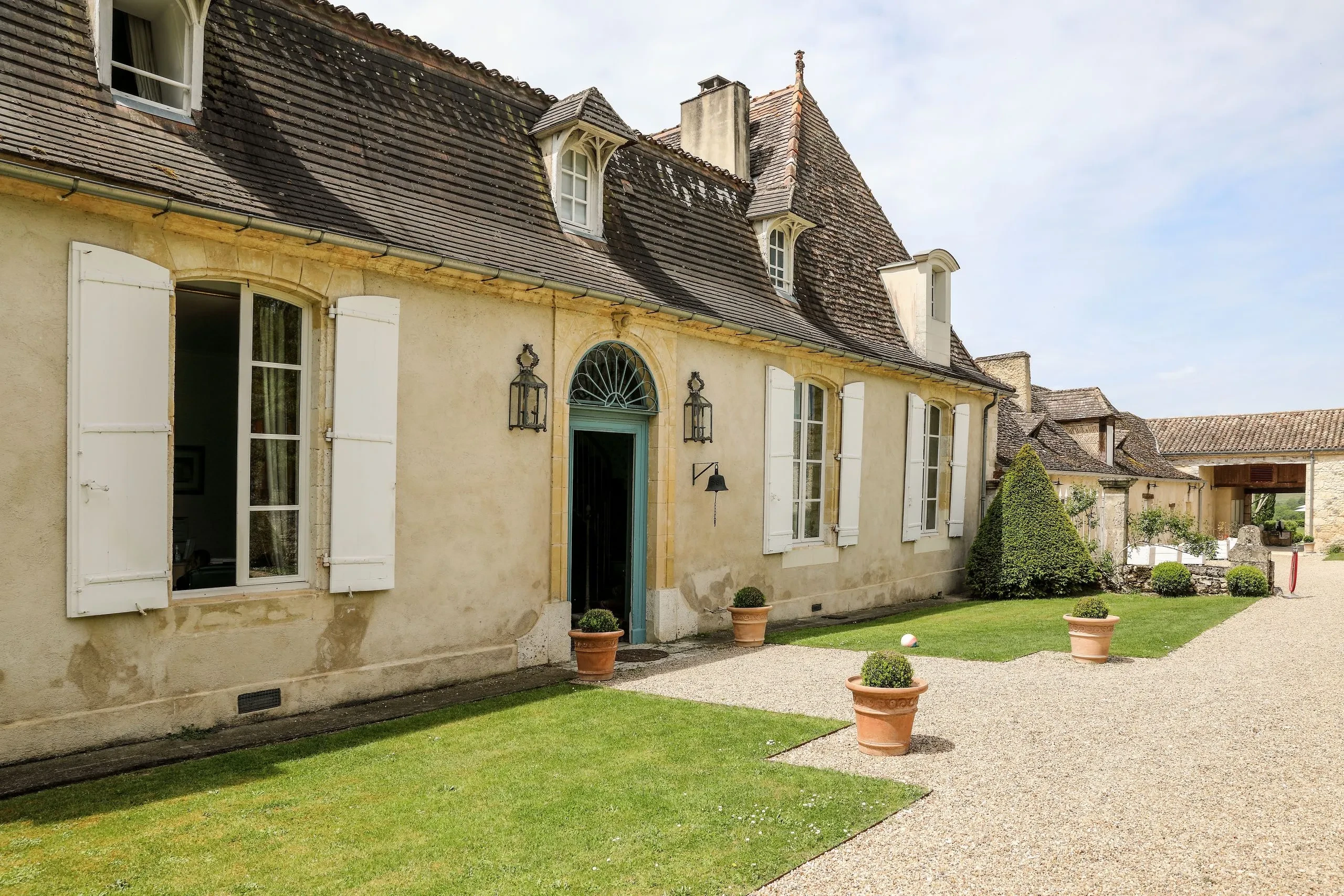 Maison ancienne avec jardin et allée de gravier.