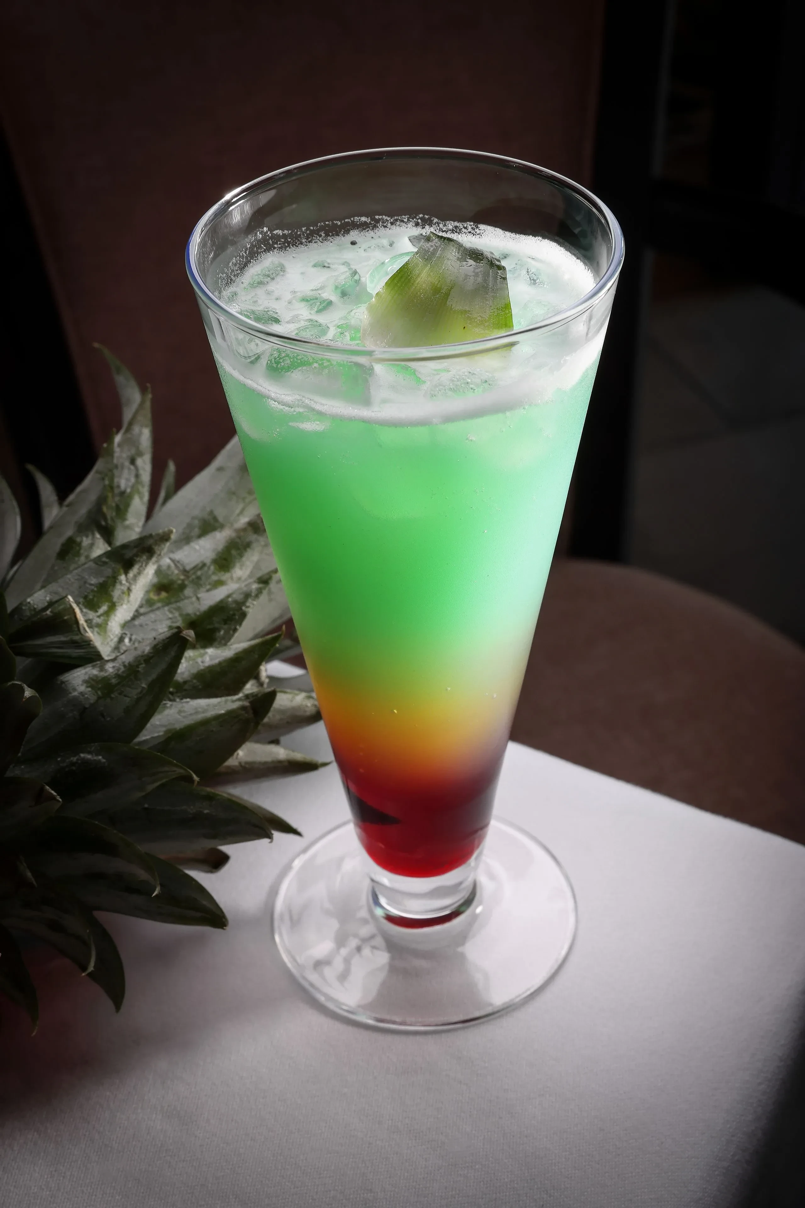 Cocktail coloré avec glace et tranche d'ananas.
