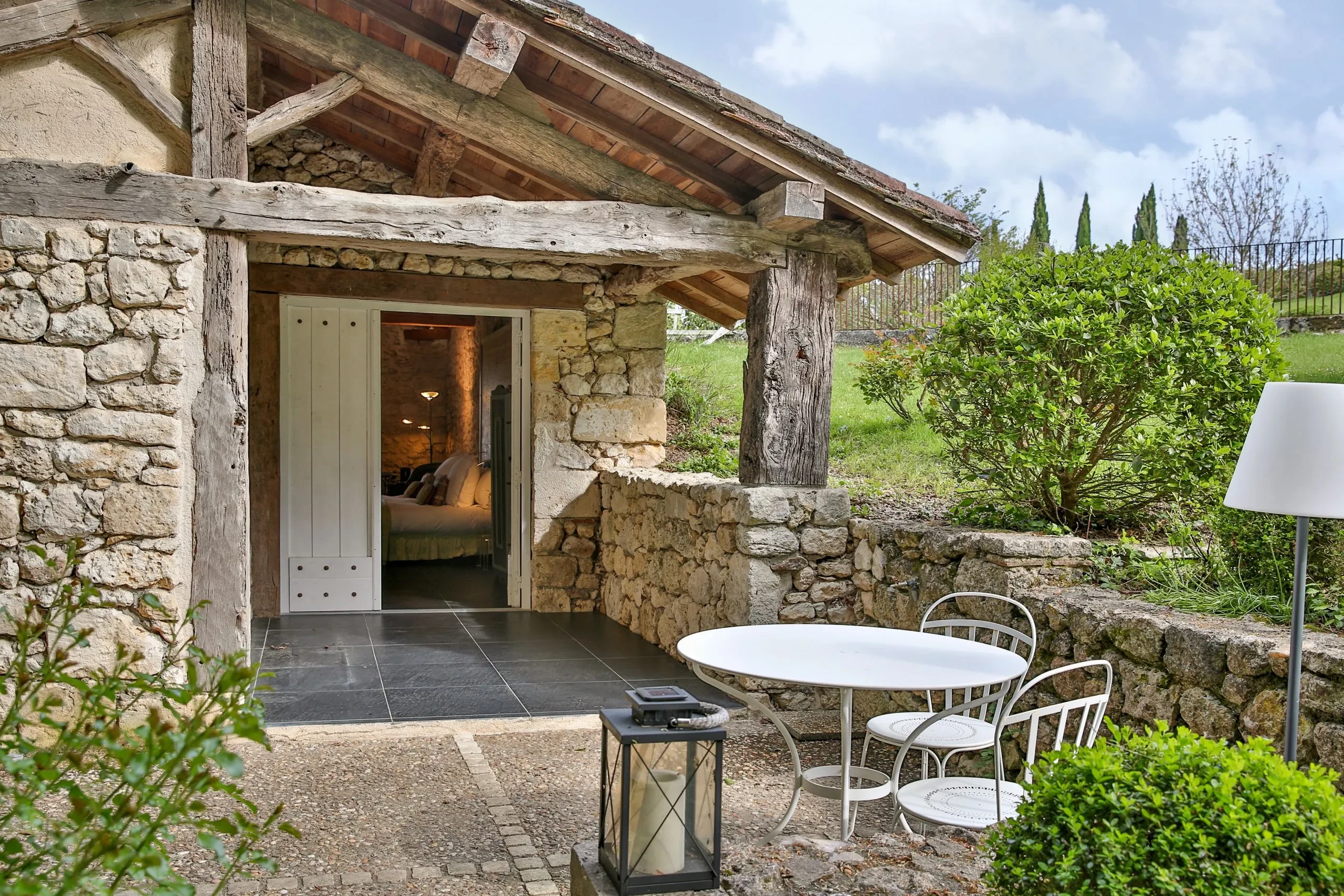 Terrasse en pierre avec table et chaises blanches.