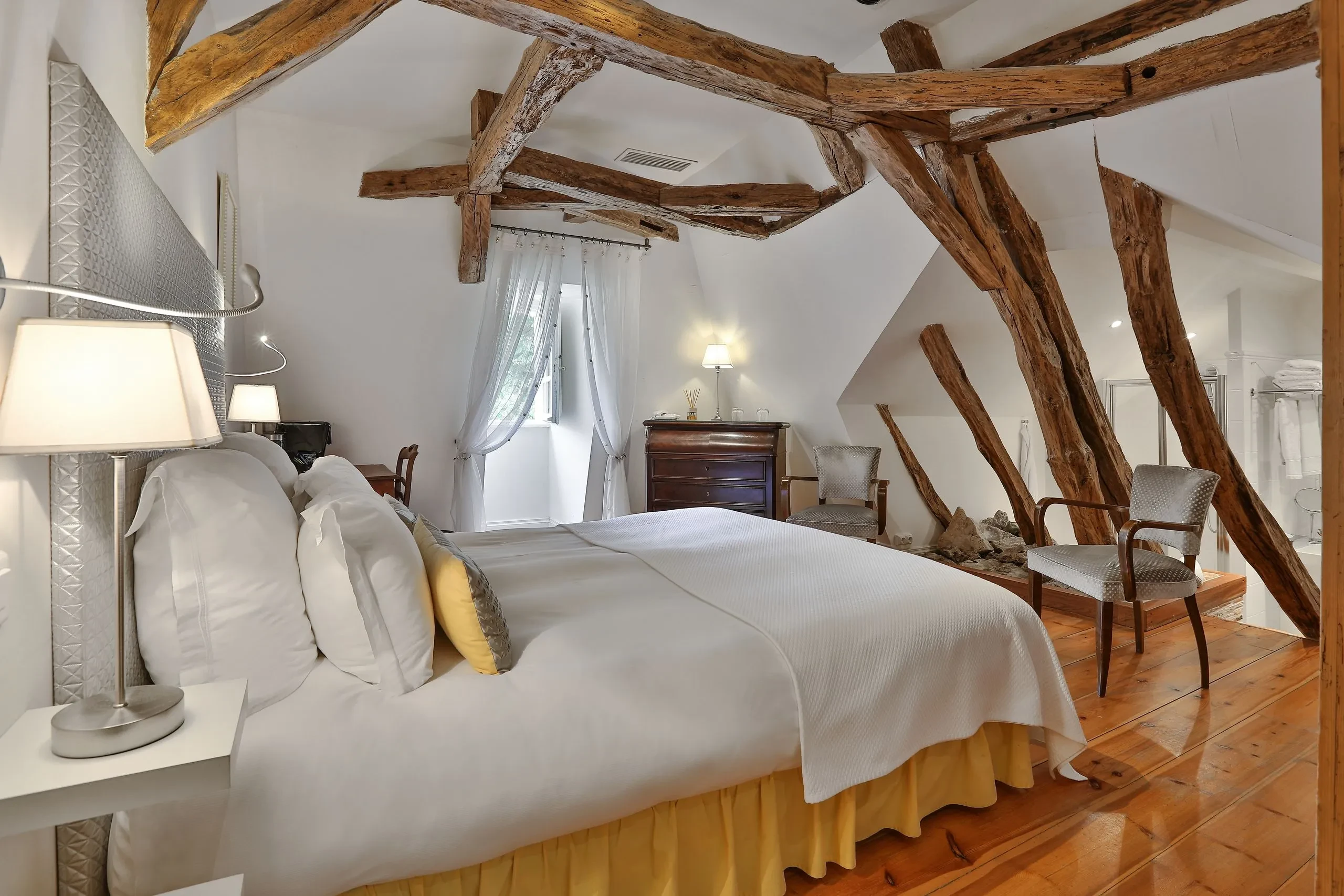Chambre spacieuse avec poutres apparentes et décoration élégante.