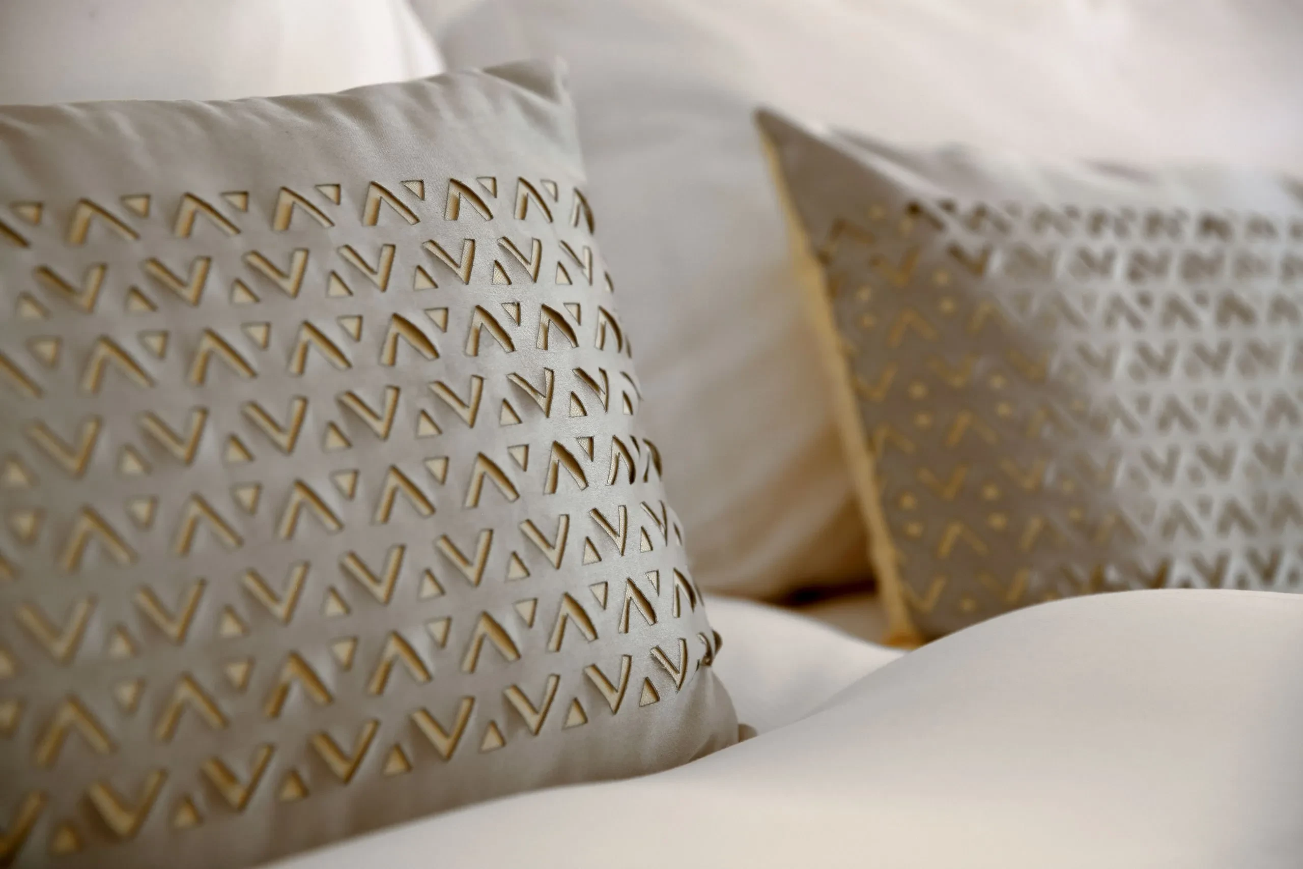 Coussins beige avec motifs géométriques.