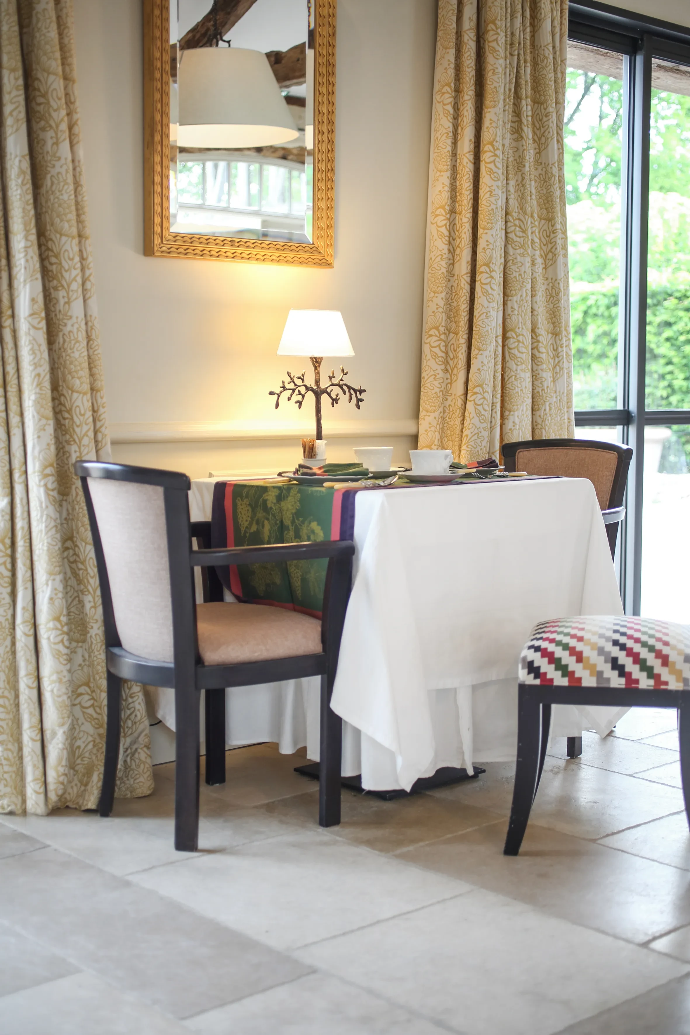 Table dressée avec lampe, miroir et fauteuils.