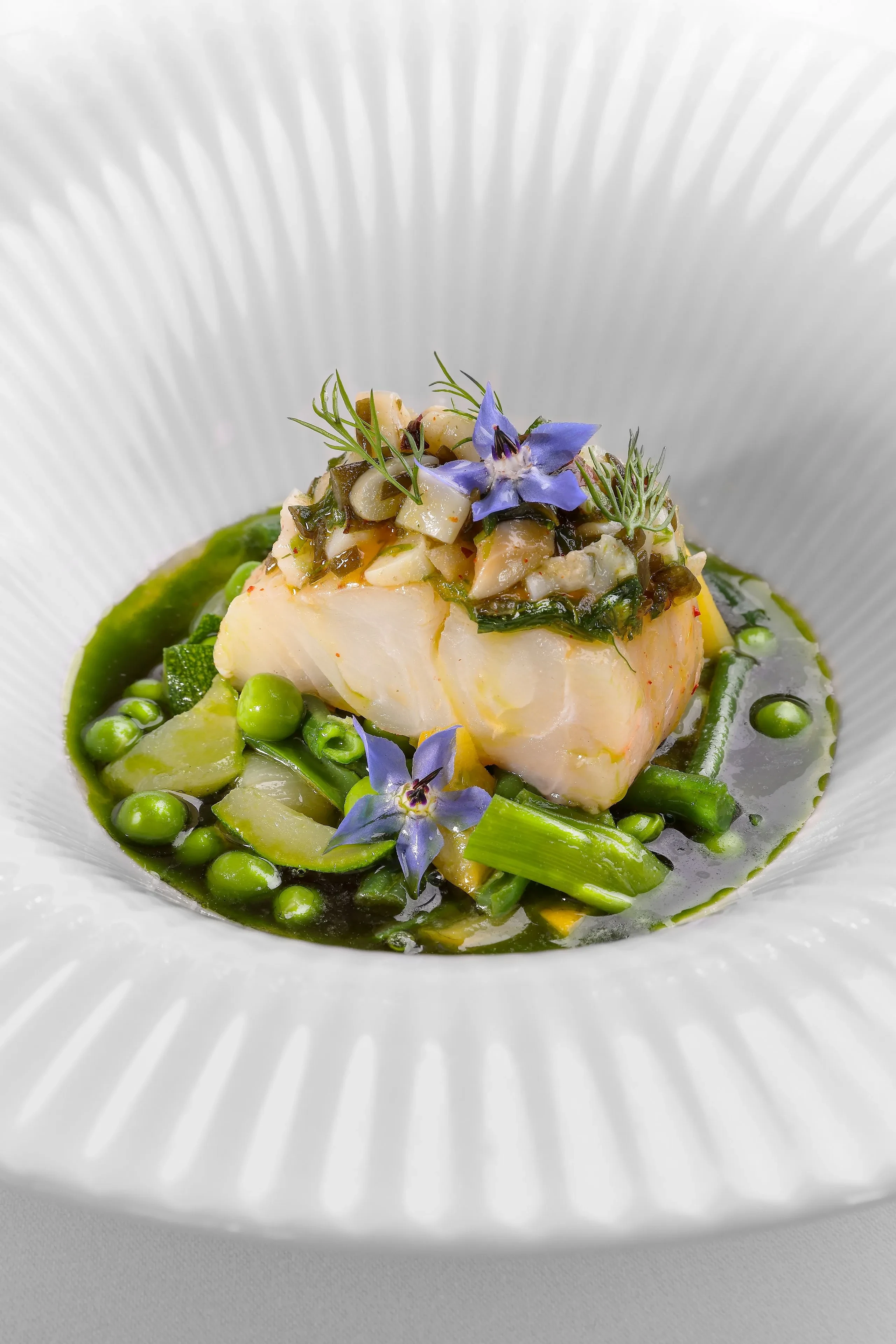Plat de poisson avec légumes et fleurs comestibles.