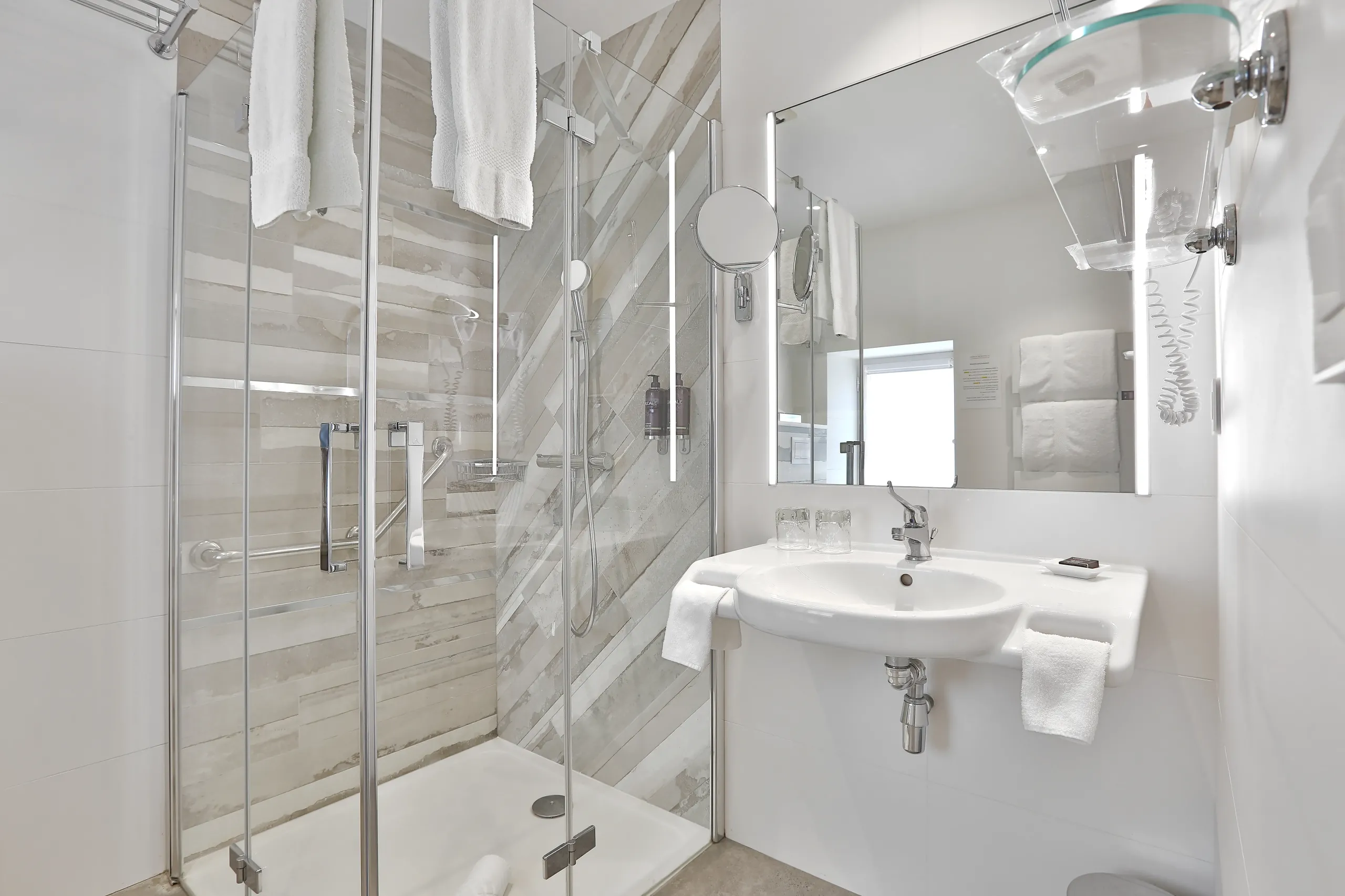 Salle de bain moderne avec douche et lavabo.
