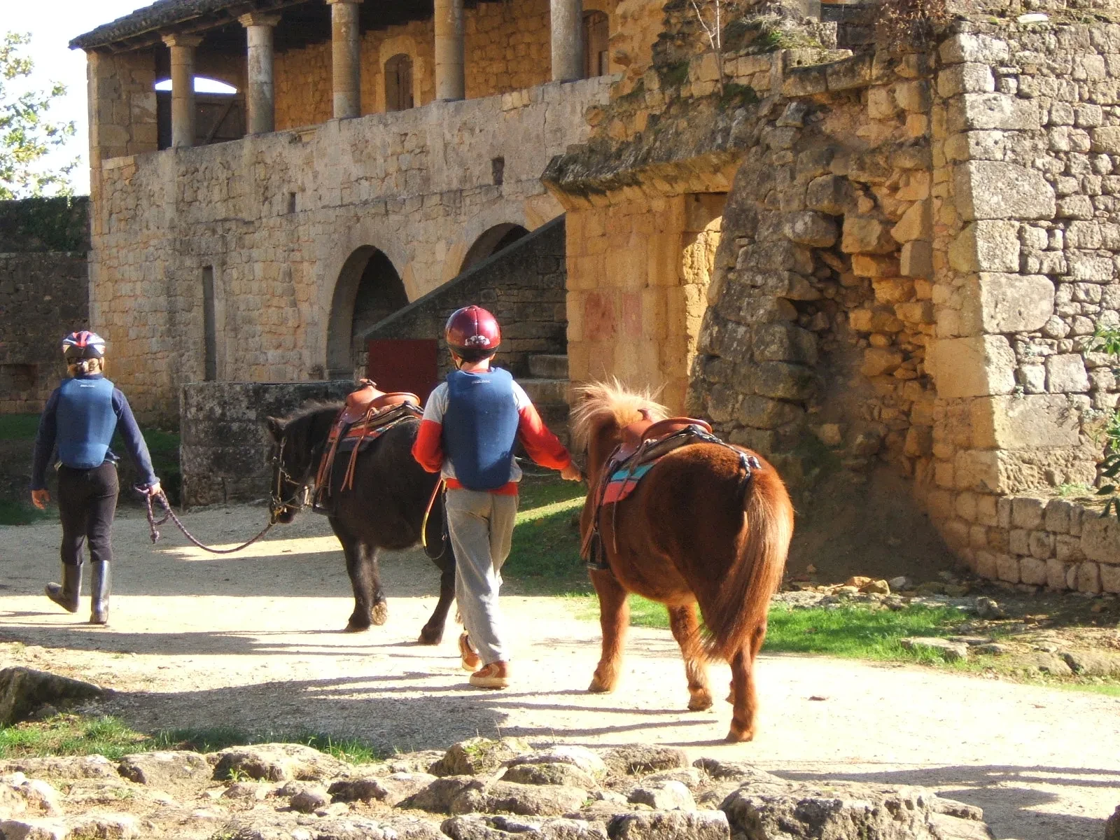 Promenade à cheval devant un bâtiment en pierre.
